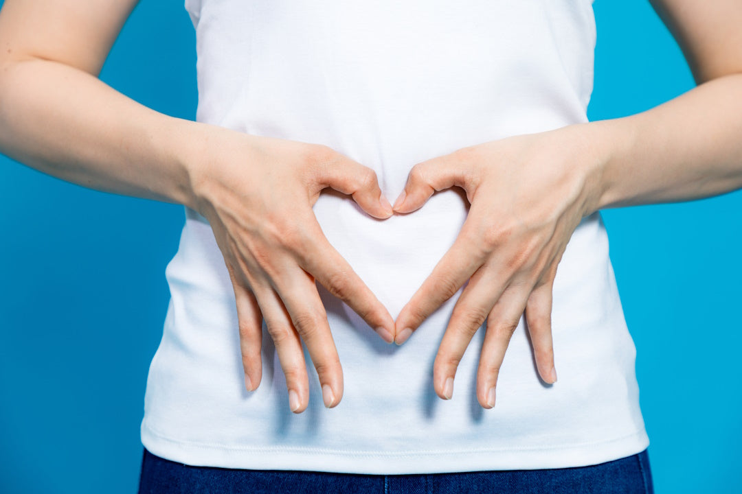 Darmflora: eine Person formt mit den Händen ein Herz über ihrem Bauch.
