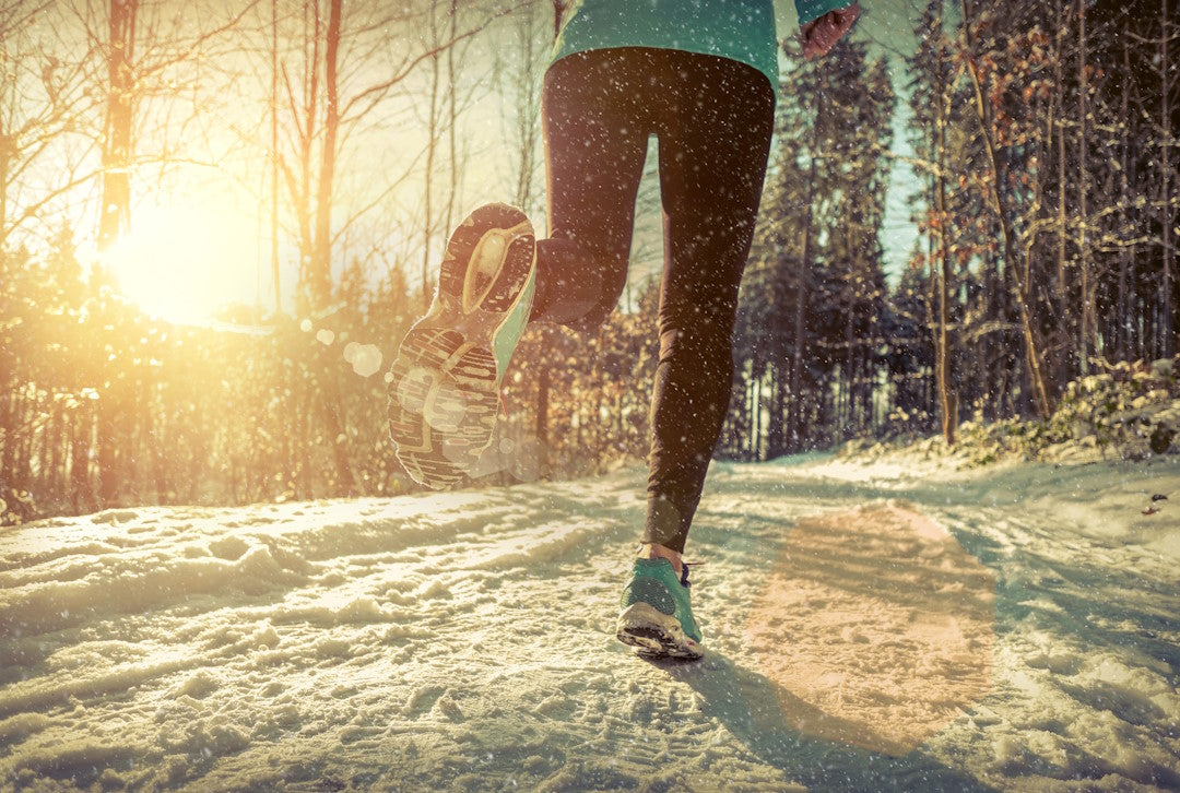 Frau geht im verschneiten Wald joggen