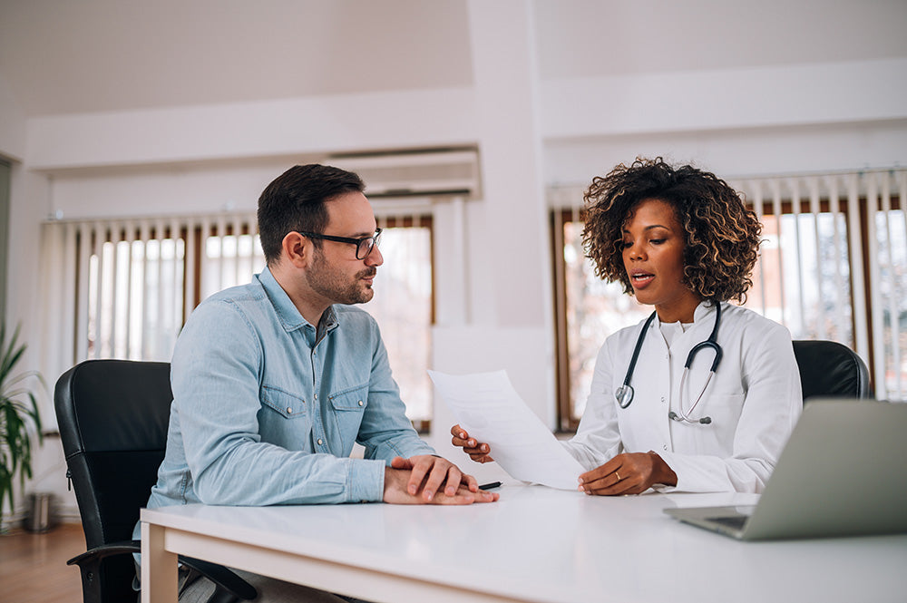 Ärztin berät ihren Patienten in einem hellen Besprechungszimmer