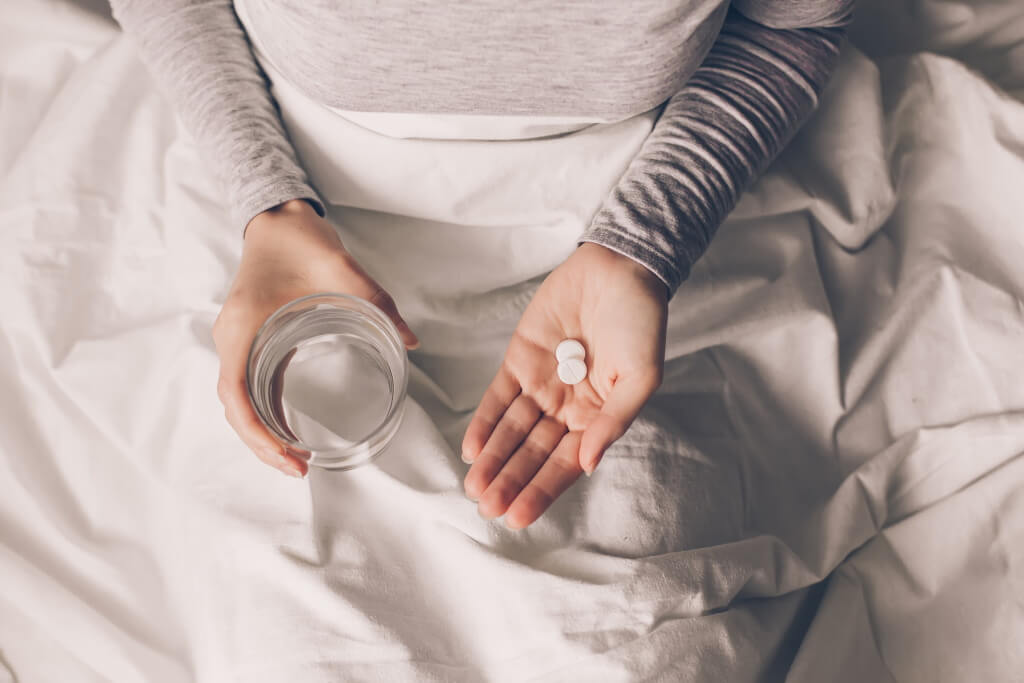 Zink und Immunsystem: Frau im Bett mit Zink-Präparaten